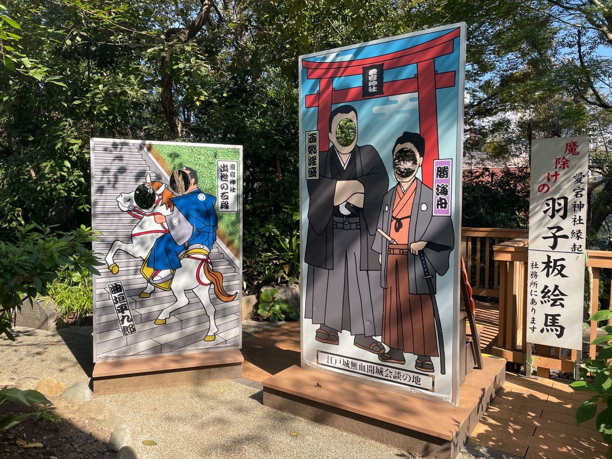 顔出しパネル。馬で石段を駆け上がる曲垣平九郎と、西郷隆盛・勝海舟。「魔除けの羽子板絵馬」の案内も