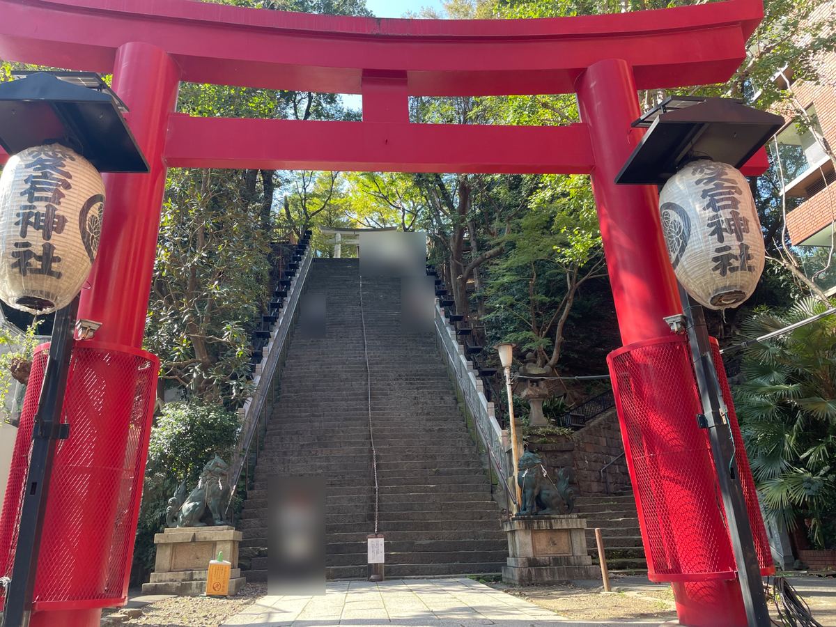正面の「出世の石段」。朱の鳥居の先に、86段の急な石段がまっすぐ続く（参拝中の方はぼかしています）