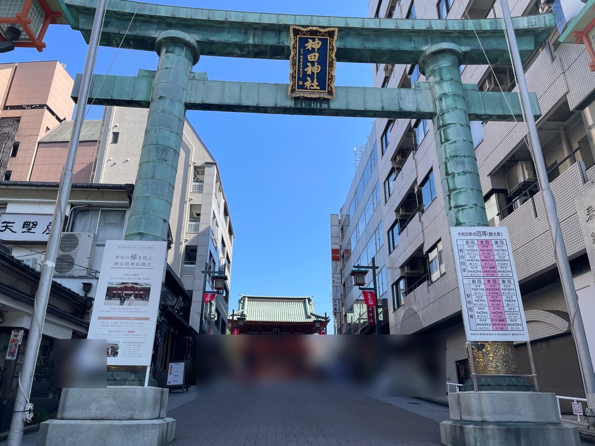 参道の入口に立つ、緑青色の大鳥居。突き当たりに随神門（まわりの方はぼかしています）