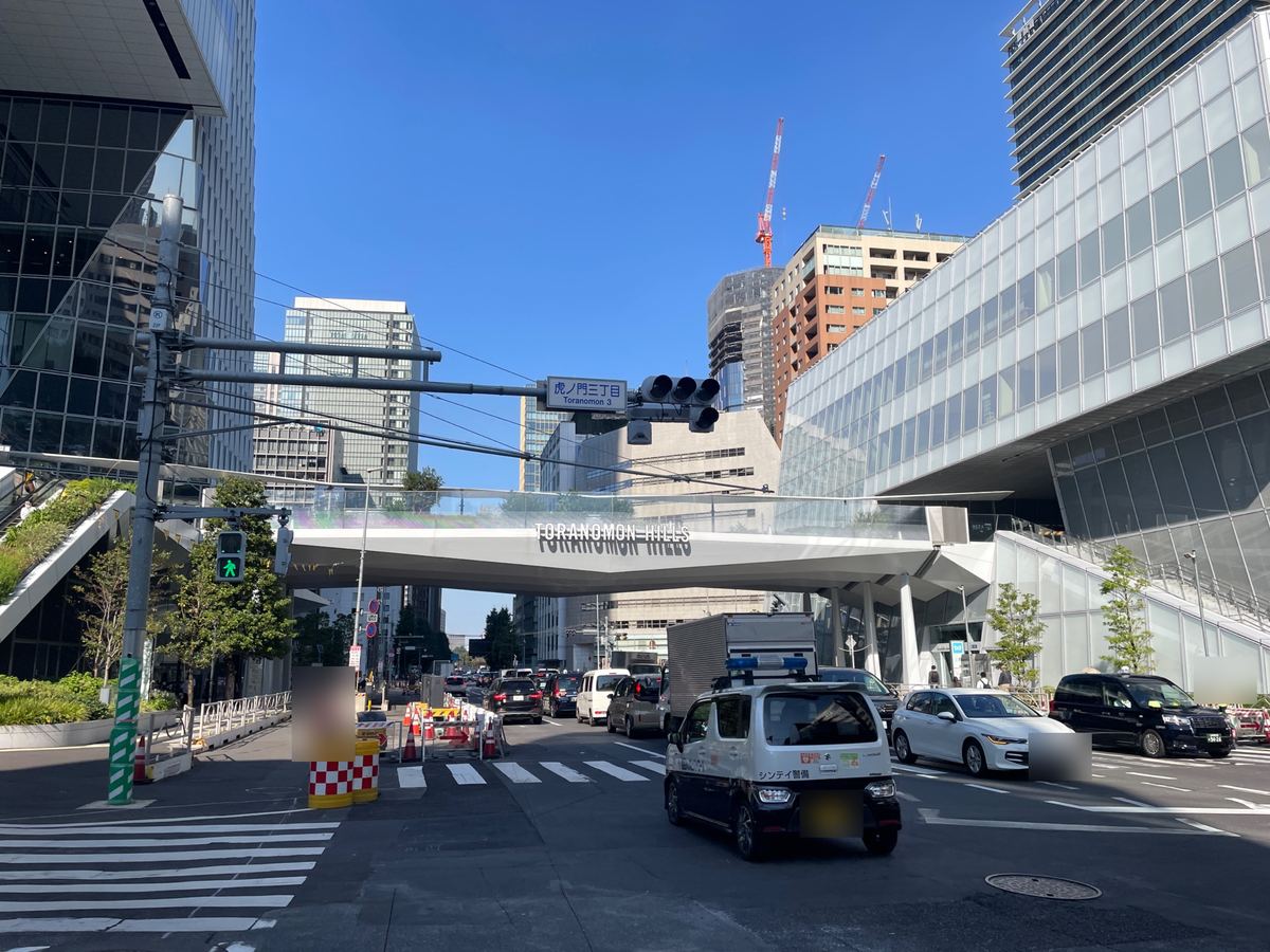 虎ノ門三丁目の交差点。正面に「TORANOMON HILLS」の歩道橋（車のナンバーはぼかしています）